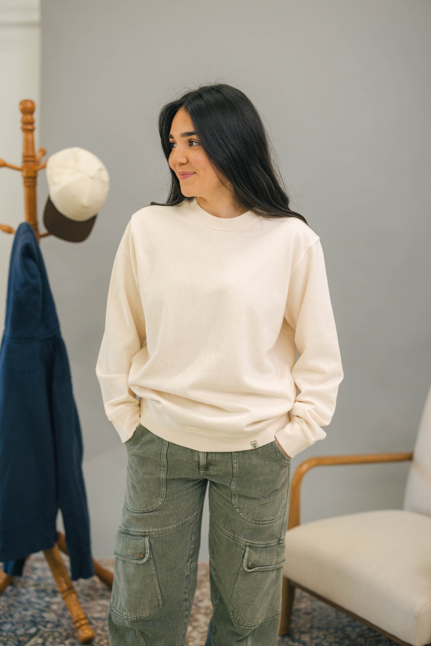 Woman standing with ivory crewneck sweatshirt and green pants