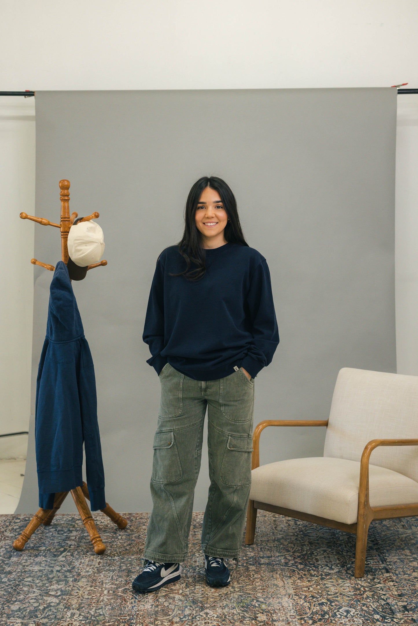 Woman standing with navy crewneck sweatshirt and green pants