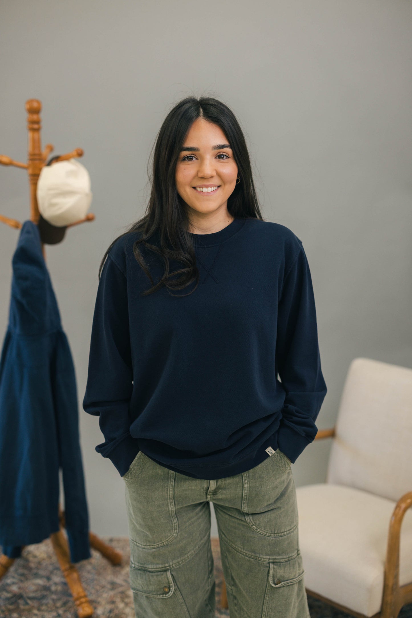 Woman standing with navy crewneck sweatshirt and green pants
