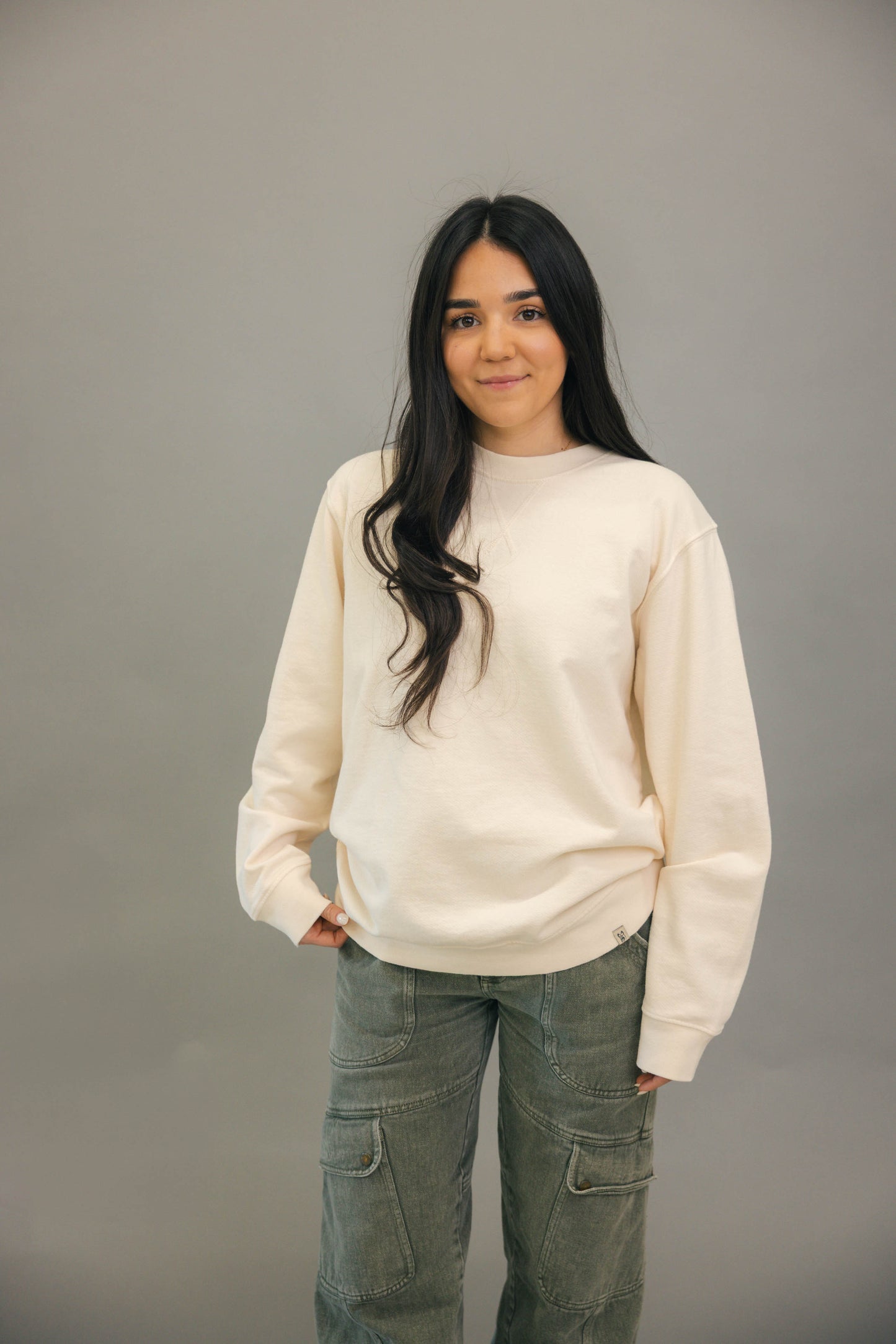 Woman standing with Ivory crewneck sweatshirt and green pants