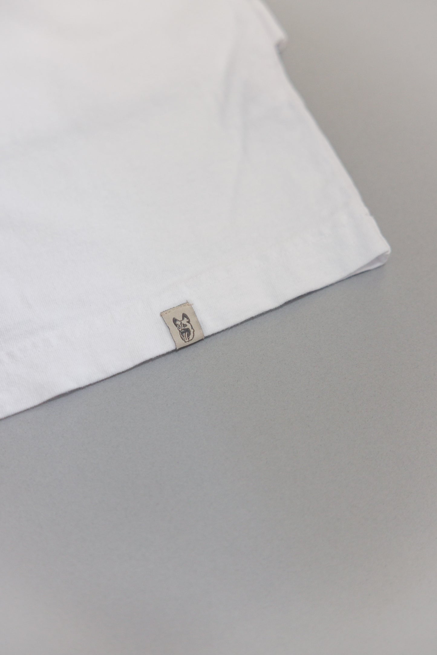 Hem of white tee with dog head label