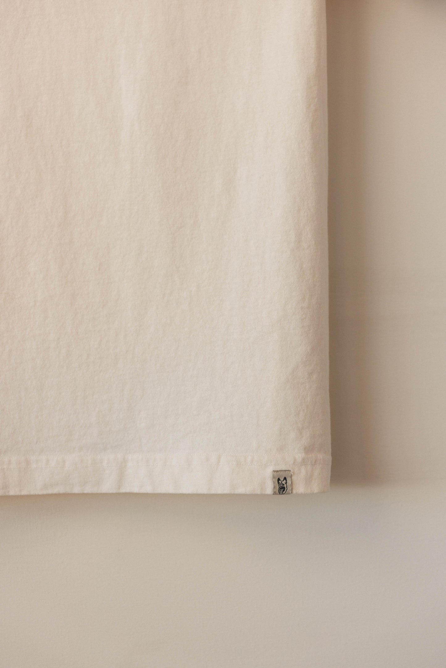 Close-up of a textured beige curtain with a small label on a neutral background