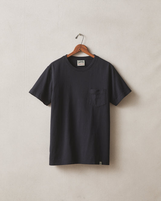 Black t-shirt on a hanger against a beige background