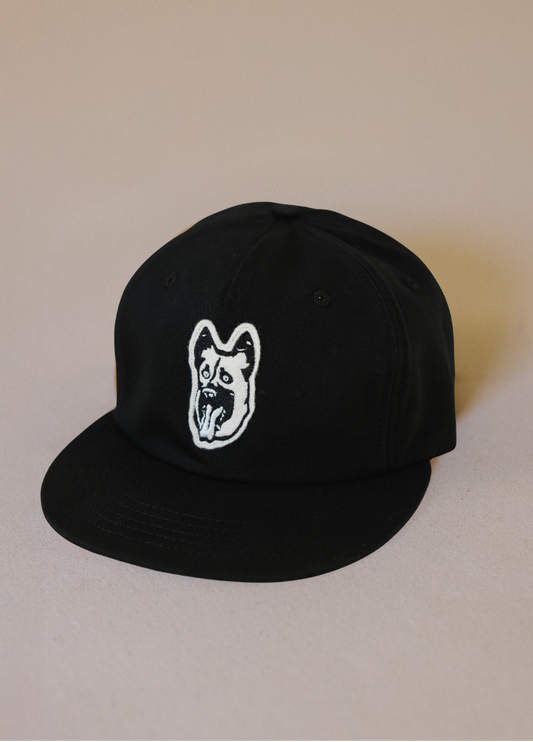 Black cap with a white logo on a beige background