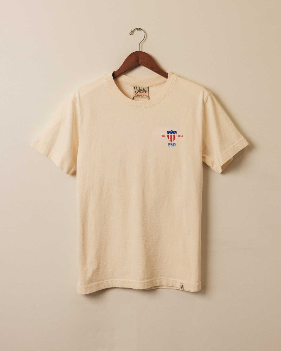 Ivory tee hanging with shield, PHL, USA, and 250 on left chest