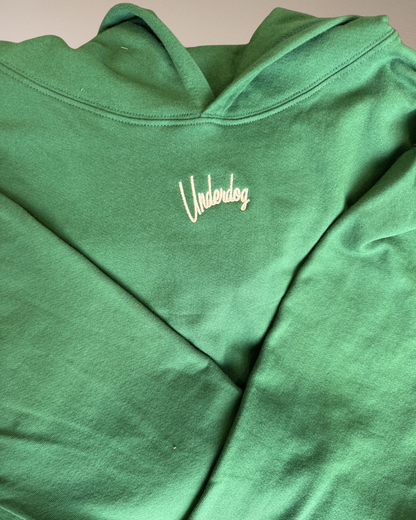 Green hoodie with 'Underdog' logo on a beige background