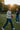 Man with tan sweatshirt playing football in the grass with bright sun above his head