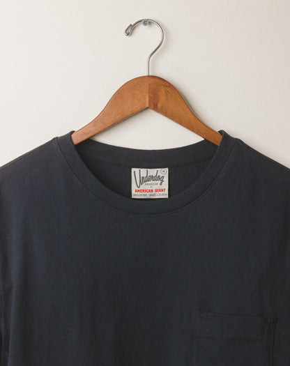 Black t-shirt with a brand label on a wooden hanger against a white background