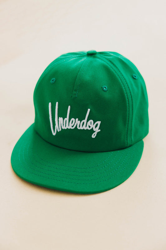 Green cap with 'Underdog' logo on a beige background