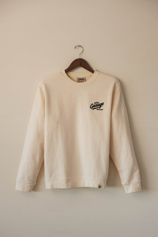 Beige sweatshirt with a logo on a hanger against a beige wall