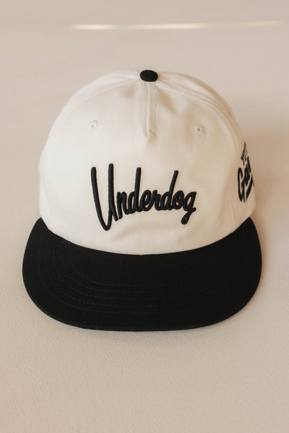 White and black cap with 'Underdog' logo on a light background