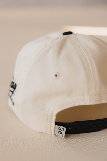 Close-up of a beige cap with a brand logo on a beige background