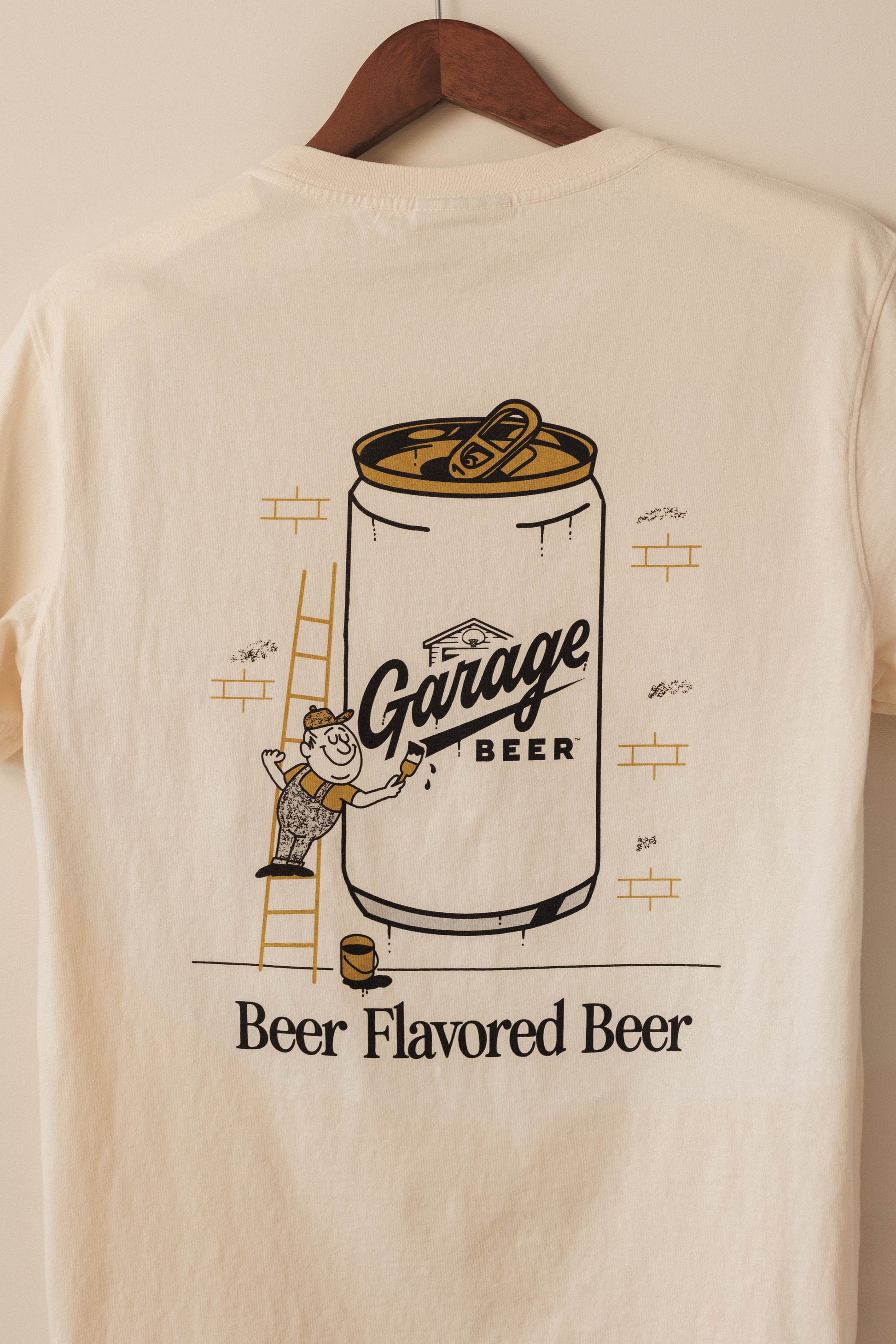 Beige t-shirt with 'Garage Beer' graphic on a hanger