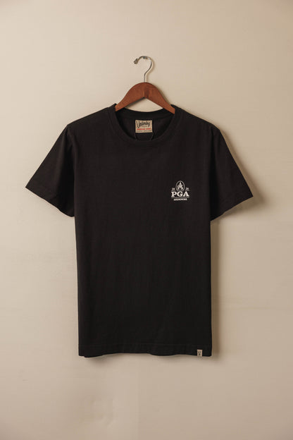 Black t-shirt with a logo on a hanger against a beige wall