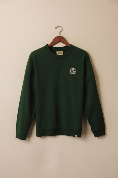 Green sweatshirt with a logo on a hanger against a beige wall