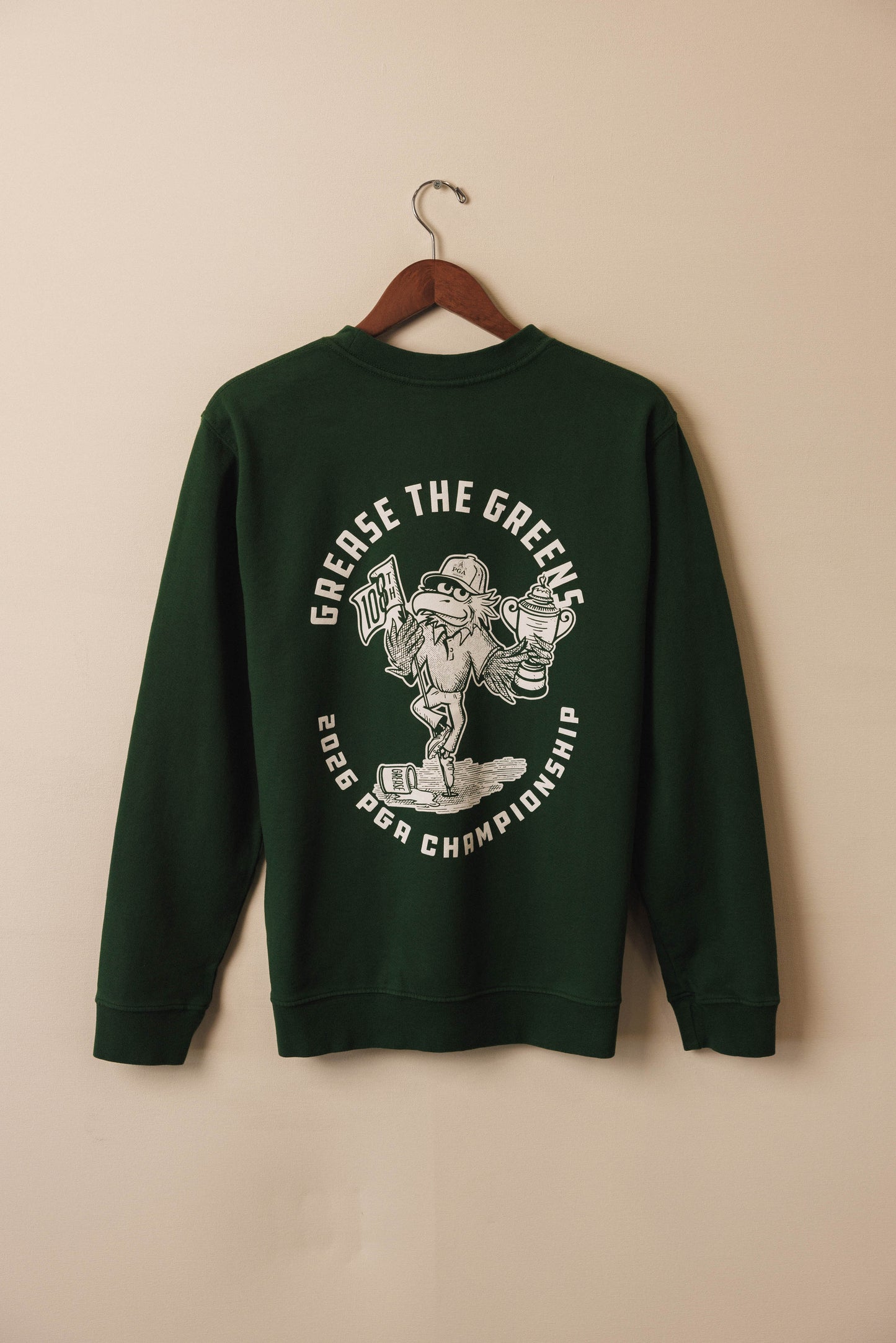 Green sweatshirt with graphic design on a beige background