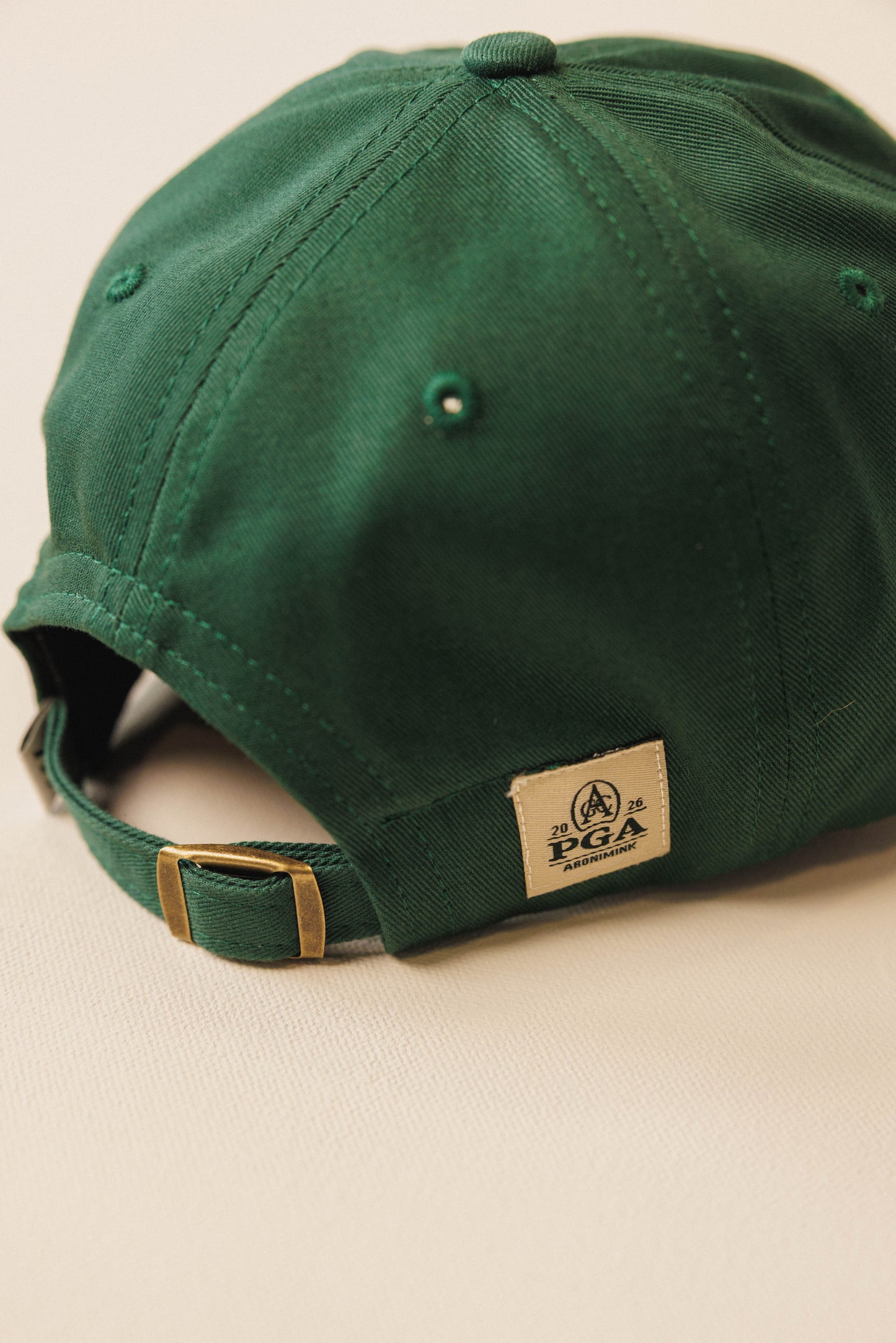 Green cap with a PGA logo on a beige background