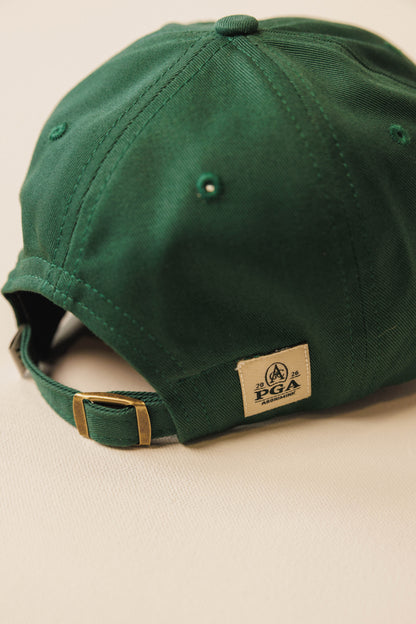 Green cap with a PGA logo on a beige background