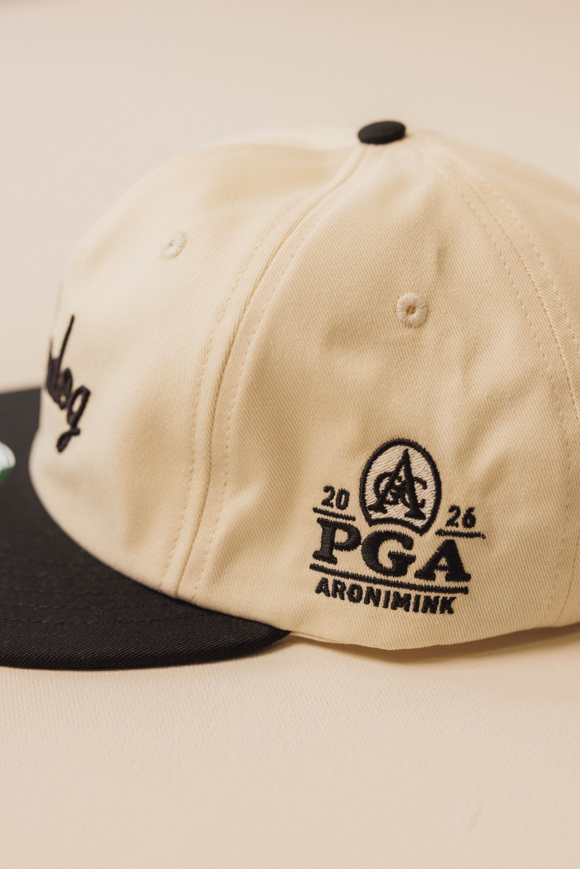 Beige cap with black logo and text on a beige background