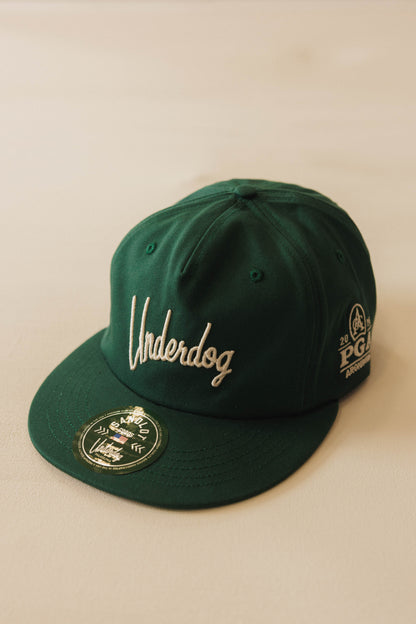 Green cap with embroidered text on a beige background