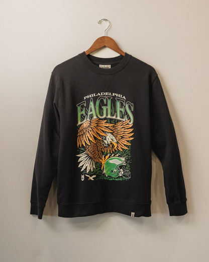 Black sweatshirt with Philadelphia Eagles logo on a hanger against a beige wall