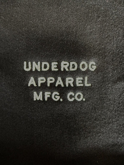 Embroidered text 'UNDERDOG APPAREL MFG. CO.' on a dark fabric background