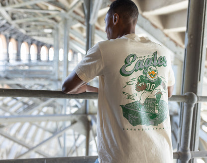 Person wearing a white t-shirt with a football player graphic and 'Eagles' text in an indoor setting.