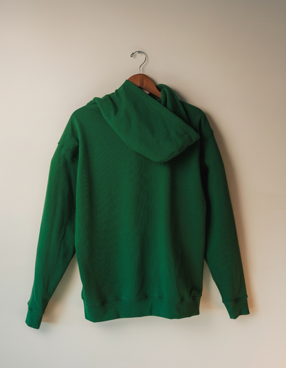 Green hoodie on a wooden hanger against a beige wall