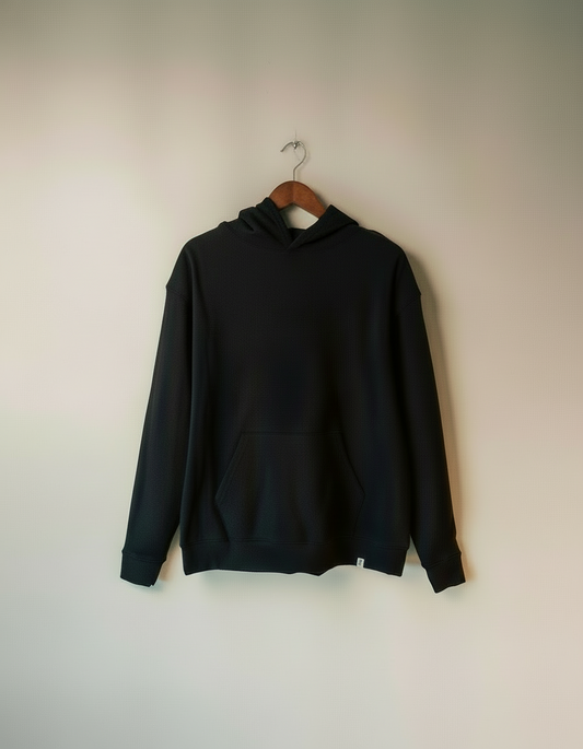 Navy hoodie on a wooden hanger against a beige wall