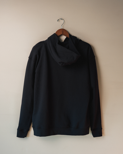 Navy hoodie on a hanger against a beige wall